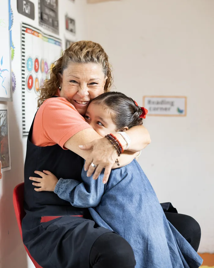 Maestra de Piruli abrazando a una niña en el salón