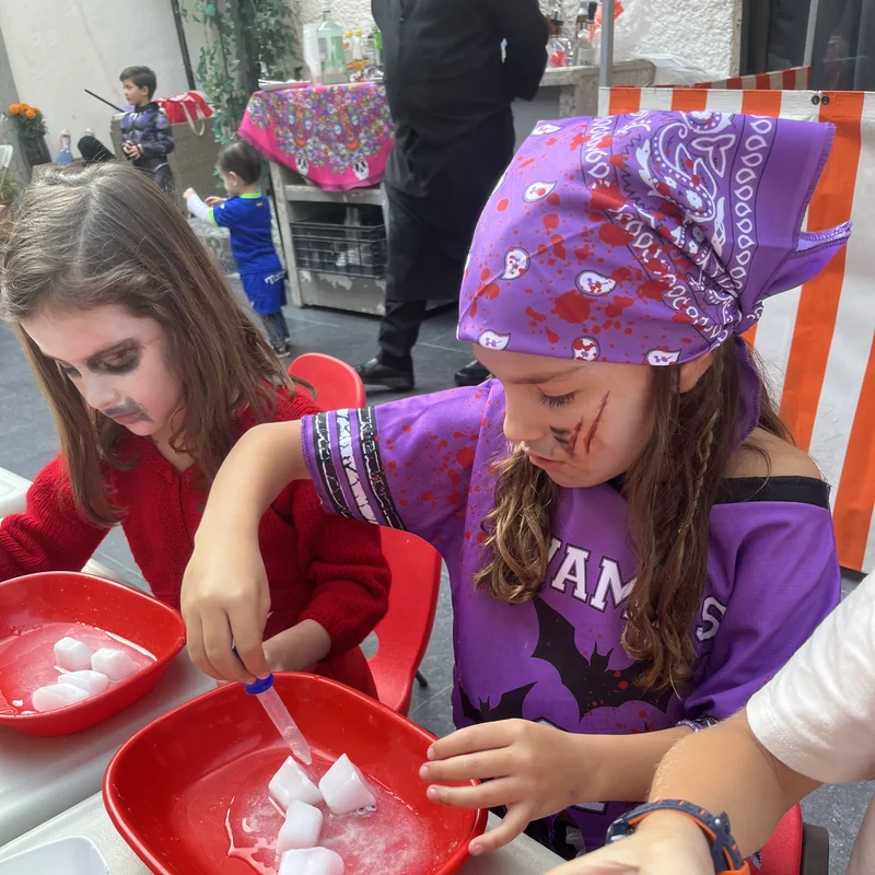 Niñas disfrazadas en una fiesta de Piruli, jugando con hielo en platos rojos